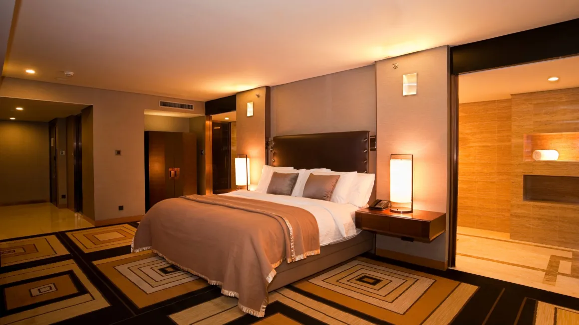 Hotel room with a bed, lit bedside lamps and a geometric-patterned carpet